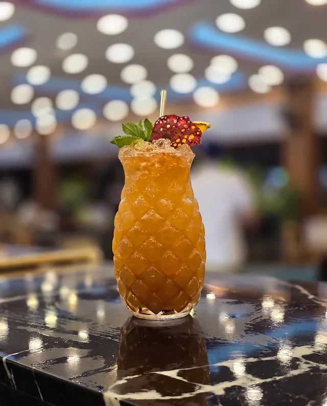 Cóctel ámbar en vaso de piña, en la barra