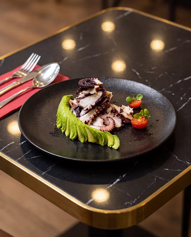 Pulpo con abanico de palta sobre la mesa de mármol