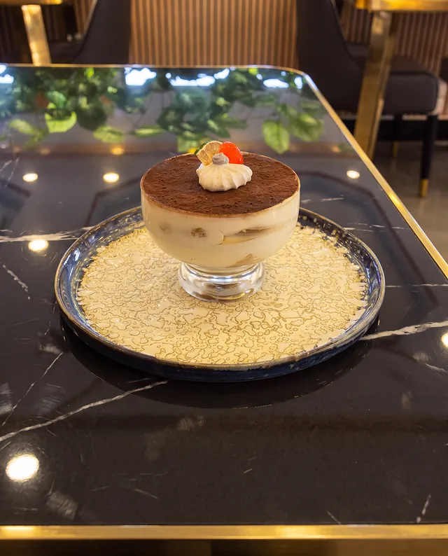Tiramisú en copa sobre plato azul